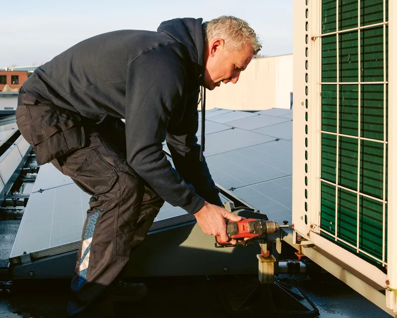 Monteur van Van Dijk Installaties werkt aan de buitenunit van een warmtepomp