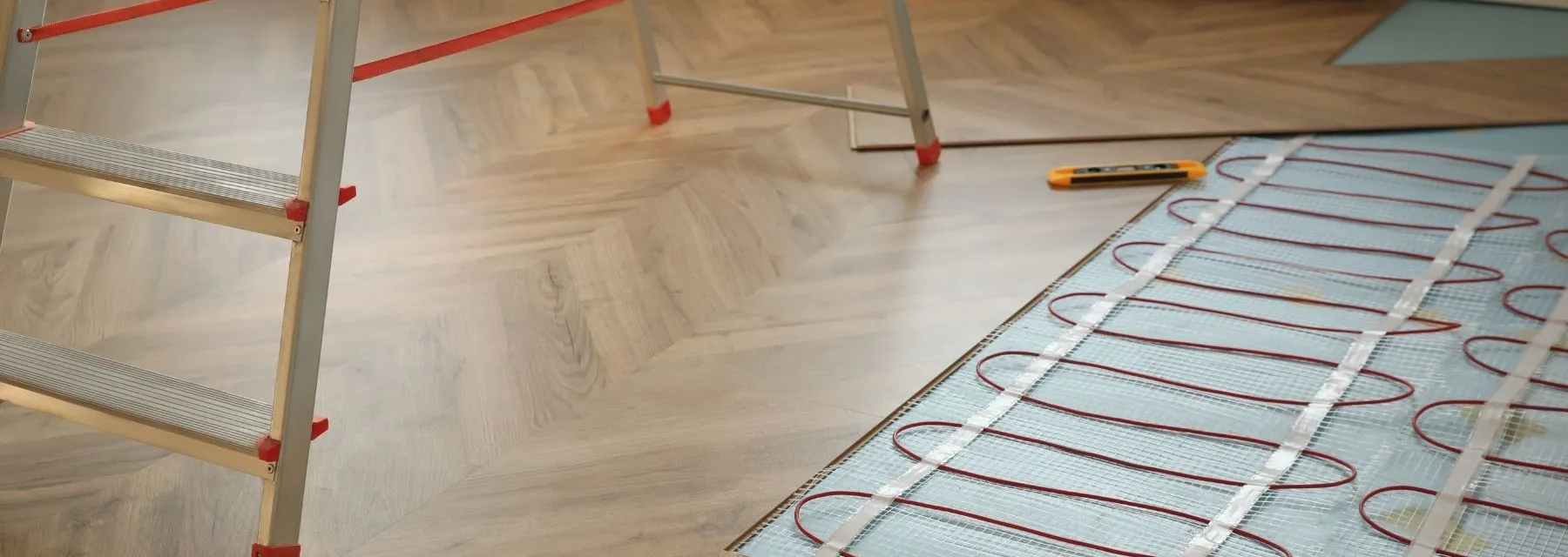Vloerverwarmingsmatten worden geïnstalleerd onder een houten vloer